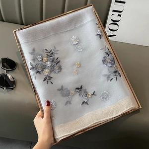 Detailed close-up of premium silk-blend scarf featuring gold floral embroidery in gift box