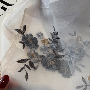Macro detail of high-quality grey silk blend scarf with metallic floral embroidery