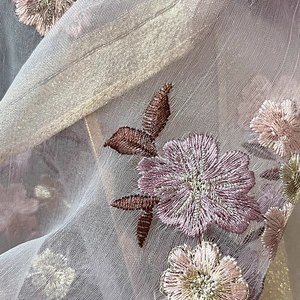 Detailed close-up of intricate floral embroidery on sheer mesh silk blend fabric