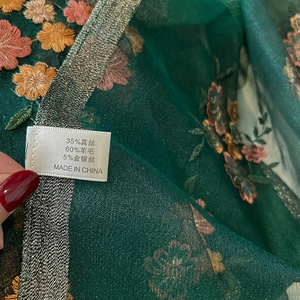 Detail of silk wool blend scarf with jacquard floral embroidery and fabric care label
