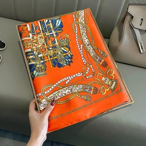 Elegant bright orange silk scarf with equestrian horse motif displayed on a tray
