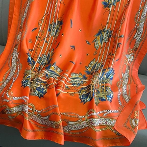 Detail of orange silk scarf with vintage equestrian harness print and satin sheen texture