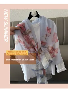 Detail of light blue chiffon beach shawl with red floral print and airy texture