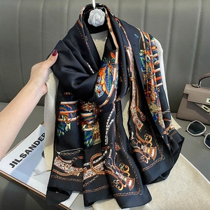 Elegant black silk scarf with golden chain and ethnic patterns on a stylish bag