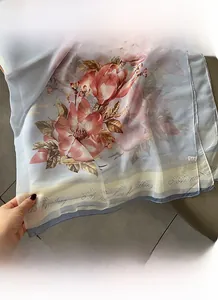 Detail of translucent silk scarf showing botanical floral print and refined edge hem