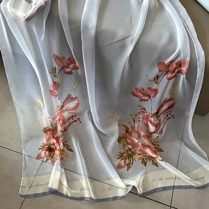 Close-up of floral print chiffon scarf with delicate 'As natural as breathing' text detail