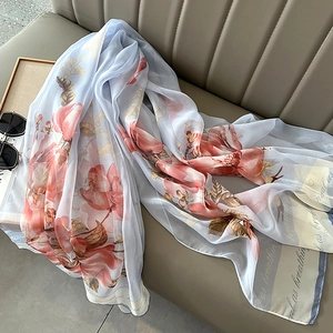 Detail of light blue floral scarf with soft pink flowers draped on a modern leather sofa