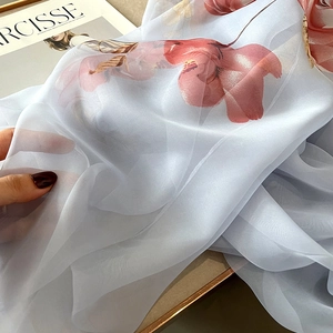 Close-up of lightweight light blue floral scarf fabric with sheer chiffon texture