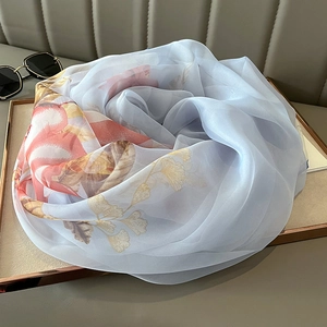 Detail view of light blue silk scarf with ginkgo leaf patterns on a display tray