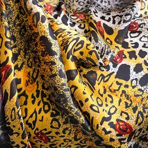 Vue détaillée de la texture du foulard en soie léopard avec des accents rouges