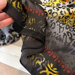 Gros plan du foulard en soie léopard montrant la texture légère et les bords rouges