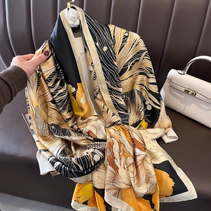 Long foulard élégant en soie à imprimé floral avec des fleurs orange sur un canapé en cuir