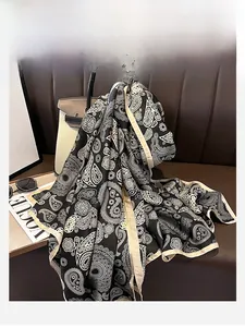 Close-up of luxury paisley silk scarf draped on a leather couch with chic accessories