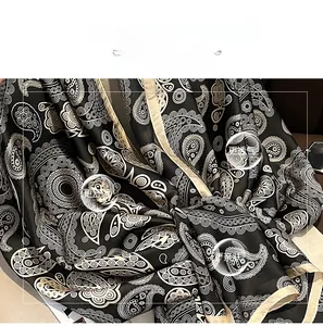 Detail of silk-like long scarf showing paisley pattern and soft satin texture fabric