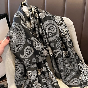Elegant black paisley silk scarf with white mandala patterns shown on a white sweater