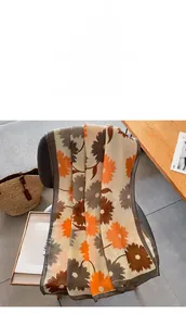 Vue détaillée du grand châle en coton et lin à fleurs orange et marron sur une chaise