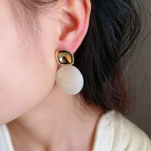 Boucles d'oreilles rétro en résine ambre et carrés dorés portées par un mannequin