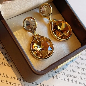 Macro shot of amber multifaceted crystal earrings with gold plating in a luxury box