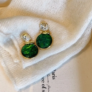 Macro shot of dark green marble pattern earrings with crystal studs on knit fabric