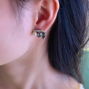 Detail of unique seesaw earrings with pearls, black teardrop gems, and micro diamonds