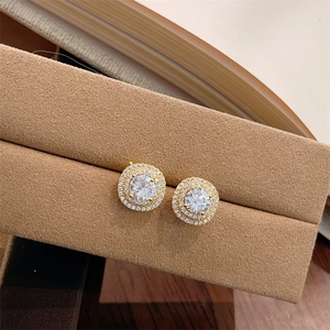 Detailed close-up of gold halo stud earrings with micro-set cubic zirconia on velvet box