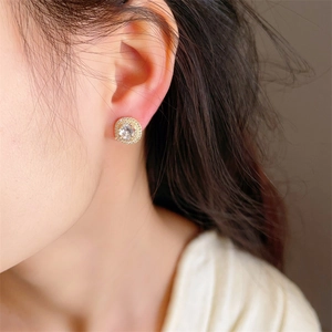 Luxurious gold-plated halo stud earrings with micro-pave cubic zirconia on a model