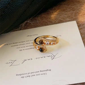Détail de la bague serpent dorée avec œil de tigre et pavé de zircons blancs