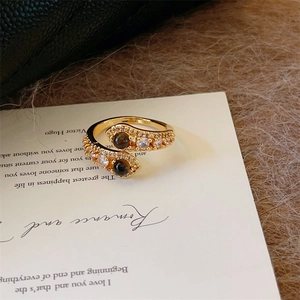 Bague bypass dorée rétro avec pierres oeil de tigre et zircons sur fond de papier ancien