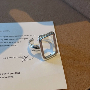 Detail van een zilveren gedraaide ring met een uniek hol rechthoekig frame bovenop