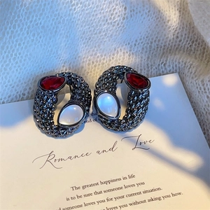 Vintage style drop earrings with red and white gemstones on a grey textured metal base