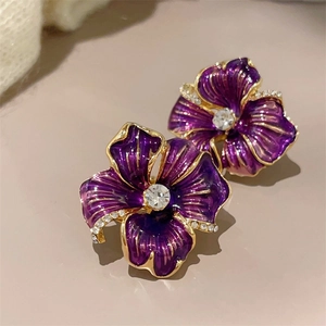 Detail of purple enamel camellia earrings with sparkling crystals and gold finish