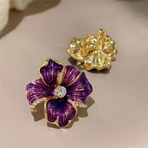 Detail of purple enamel camellia earrings with crystal accents and gold-plated backing
