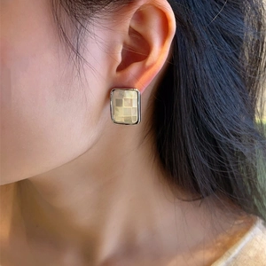 Close-up of rectangular 925 silver earrings with white mother-of-pearl mosaic on model