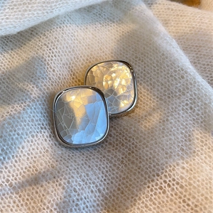 Macro shot of square silver-edged earrings with natural white shell crackle texture