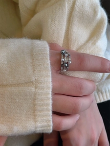 Detail of silver-toned multi-layer ring with pearls and zircons on a knitted background