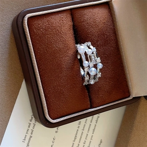 Detail of a triple-layer silver ring featuring white pearls and zircon in a leather box