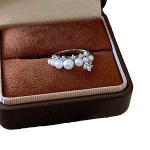 Polished silver ring with five white pearls and sparkling zircons on dark velvet