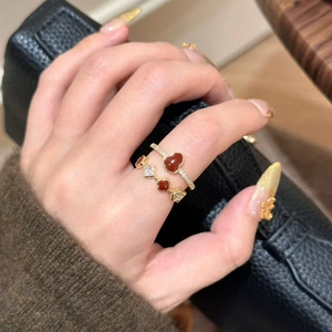 Macro shot of two gold rings with red heart and clover gems on model hand
