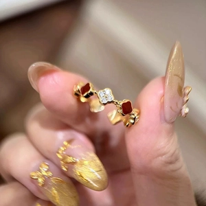 Detailed view of red and zircon clover charms on a gold-plated adjustable ring