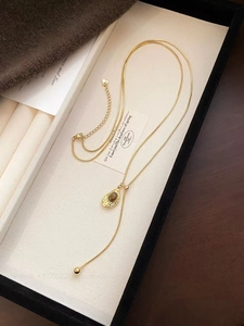 Detailed macro view of a vintage gold snake chain necklace with brown tiger eye drop pendant