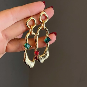 Detailed macro view of irregular geometric earrings with red and green gemstones