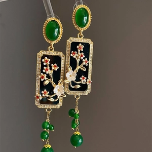 Detail of vintage flower plaque earrings with green gems and dangling beaded tassels