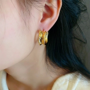 Golden irregular wavy C-shape earrings with textured metal finish on a female model
