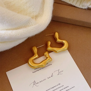 Gros plan de boucles d'oreilles cœur dorées mates sur carte avec fond en tricot