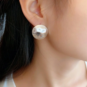Close-up of silver geometric stud earring featuring a unique hammered brushed texture