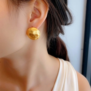 Detail of matte gold geometric earring with brushed hammered texture on female model