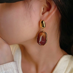 Irregular resin oval drop earrings with gold metal accents on female model