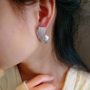 Elegant curved zircon pavé stud earrings with white pearls shown on a female model