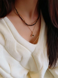 Detailed view of layered tiger eye bead necklace on white knit sweater for autumn