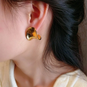 Boucles d'oreilles minimalistes en or 18 carats brossé portées sur un modèle